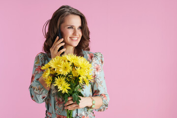 happy trendy woman in floral dress talking on phone on pink