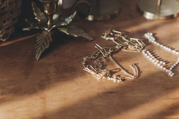 Modern gold and pearl accessories on table with vintage candlesticks. Necklace and ring in sunshine