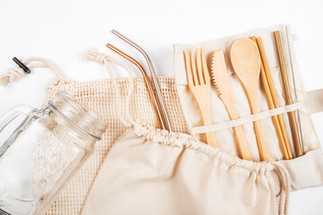 Flatlay with wooden cutlery and mason jar in fabric bags isolated on white background. Zero waste concept.