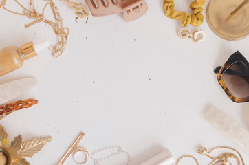 Feminine summer essentials flat lay. Gold jewellery, boho accessories, sunglasses, cosmetics