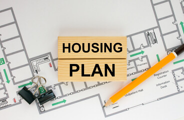 Construction drawings and wooden bars with text Housing Plan and paper clips