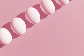 Easter Concept. White fresh eggs in isometric line on pink paper background. Minimal food concept. Copy space. Flat lay.