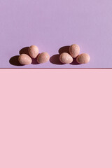 Abstract Easter layout with eggs and trend summer shadows on two tone pastel pink and purple background. Vertical photo. Copy space. Flat lay.