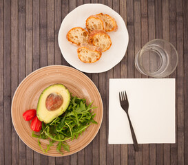 half an avocado, arugula and cherry tomatoes on plate