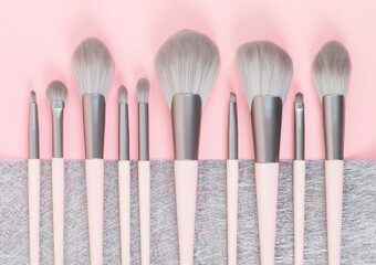 Set of professional makeup brushes on pink and gray colored composed background. Creative concept of beauty. Copy space. Flat lay.