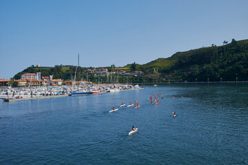 Fototapeta na wymiar View of the Ribadesella estuary (Ribeseya) with athletes practicing canoeing. Town in eastern Asturias.