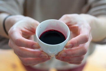 woman holding a small cup of coffee, juice in her hands. Blurred background.  