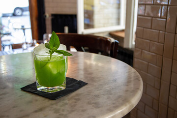 green mojito cocktail with ice and mint on a marble table
