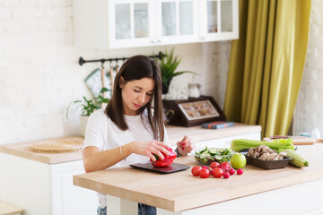 Obraz na płótnie Canvas a woman prepares salad and weighs pepper on kitchen scales. Product weighing. Smart eating. diet planning. calories control for wellness.