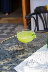 Green cocktail with mint, outdoor seating. 