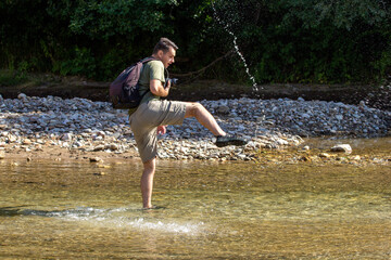 A young man dancing on the water on a sunny day, on a mountain river. © NAIL BATTALOV