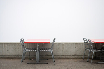empty chairs and red tables in Switzerland with a fog white wall up in the mountains. No people