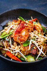 Modern style traditional Thai phak kung curry with barbecue king prawns and noodles as close-up in Nordic design bowl with copy space