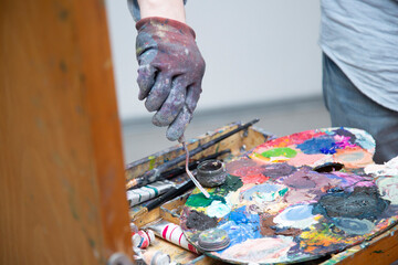 The artist paints with a brush on canvas with colored oil paints