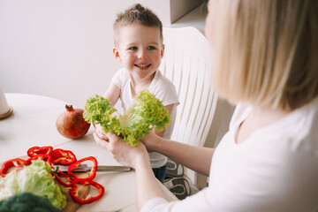 Cute boy preparing a salad of fresh vegetables. Boy preparing a salad for his mother
