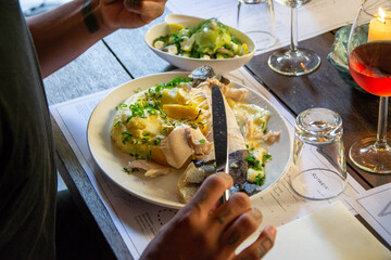 man eating fried fish with mashed potatoes, cucumber salad and red wine in restaurant. 