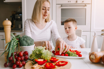 mother with little son preparing a salad of fresh vegetables