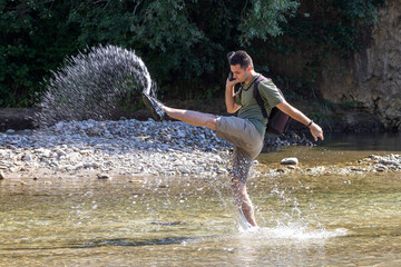 A young man dancing on the water on a sunny day, on a mountain river. © NAIL BATTALOV