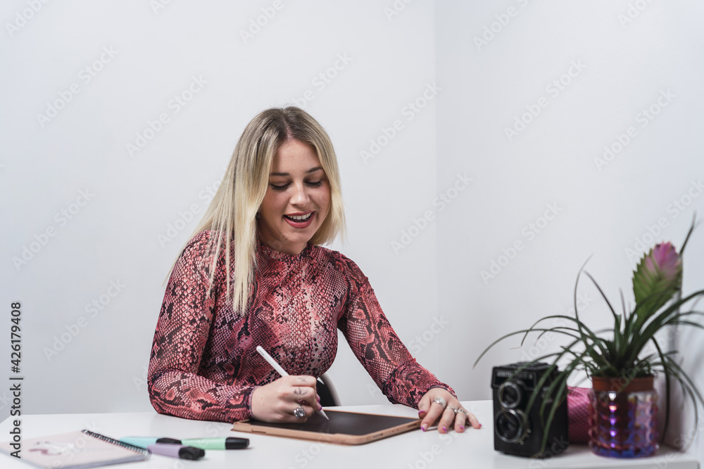 Wall mural Young Caucasian female from Spain working and taking notes on a tablet with a smartpen