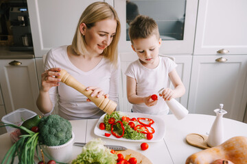 mother with little son preparing a salad of fresh vegetables