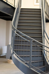 Architectural curved metal staircase in gallery building with rails. 