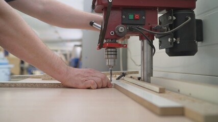 The process of manufacturing cabinet furniture from chipboard on a modern automatic drilling and milling machine. Modern automatic woodworking machine. Drilling machine in the furniture industry.