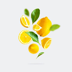 Juicy ripe flying yellow lemons, green leaves on light gray background. Creative food concept....