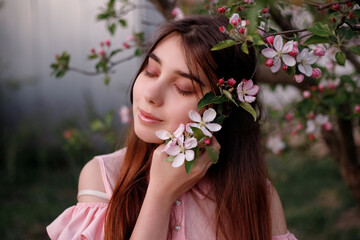 Beauty portrait redhead woman in spring in the branches of an apple trees