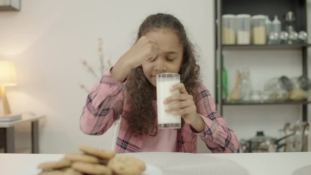 Unhappy little girl drinking glass of milk with disgust, lactose intolerance
