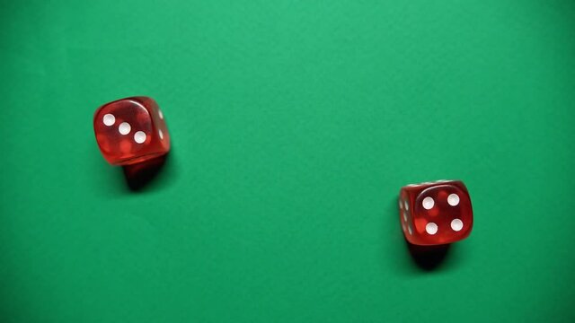 Red dice falling on green table. The Numbers 4 and 3 Appear on the Dice.