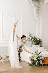 Dancer makes twine in white dress and reaches for flowers