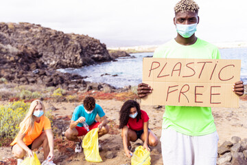Volunteer people collecting trash on the beach. Trash-free seas concept.  African boy holding a plastic free banner.
