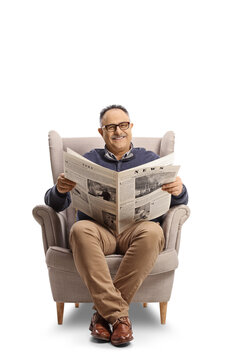 Cheerful mature man reading a newspaper and smiling seated in an armchair