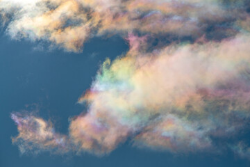 Unique phenomena of iridescent clouds with rainbow colors in natural form. Blue sky with colourful clouds in front. 