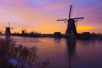 Fototapeta na wymiar Windmills at sunset in Kinderdijk near Rotterdam in The Netherlands during winter with ice on canal