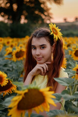 beautiful redhead girl in a yellow t-shirt on a field with sunflowers at sunset