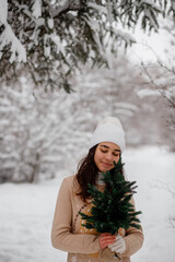 beautiful girl with sledges, christmas tree and gifts in winter in a snowy forest