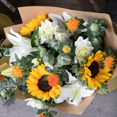 Wedding bouquet of sunflowers, white chrysanthemum, lilies, eucalyptus and marigold wrapped in craft paper