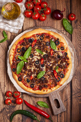 Beef barbeque Pizza with minced meat, red onion, chili pepper, black olives and mozzarella cheese. American style homemade pizza. Freshly baked and served with basil leafs.