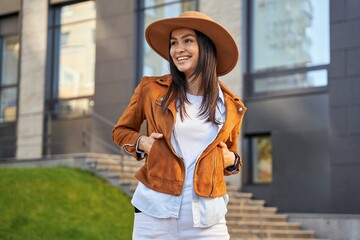 Smiling brunette lady in jacket looking away outdoor