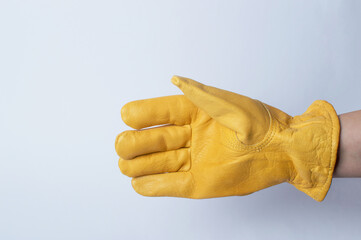 Yellow leather rough glove on the hand of a worker on a gray background. Construction protective overalls. Copy space. Close-up.