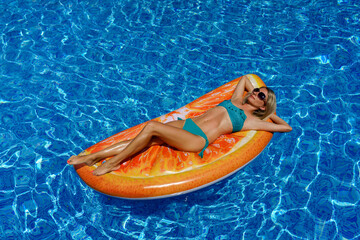 Beautiful slender girl sunbathes on an inflatable mattress in the pool. Relaxing vacation during your summer vacation.