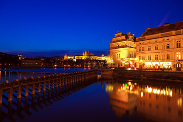 Prague at night along the river with Cathedral and Castle lit up (Czech Republic)