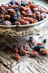 Dried grapes in silver bowl on wooden background, raisins