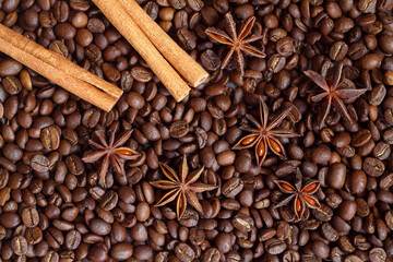 Cinnamon sticks and anise stars spices on roasted coffee beans background.
