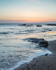 Sunrise view from Old Hartley Bay, Northumberland, England, UK, looking towards St Marys Lighthouse, Whitley Bay and the open sea.