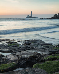 Fototapeta na wymiar Sunrise view from Old Hartley Bay, Northumberland, England, UK, looking towards St Marys Lighthouse, Whitley Bay and the open sea.
