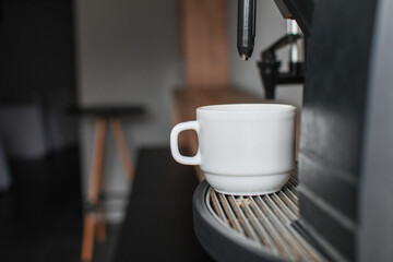 Detail of a coffee maker machine with a cup of coffee. Selective focus. 