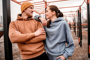 Cute couple in sports outfit doing morning workout outdoors. Young man and woman stretching they muscle before running on street sports ground. Staying fit and healthy concept.