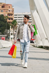 elegant young man on a shopping day walking through the streets of the city with many shopping bags in his hands, shopping bags of many colors.